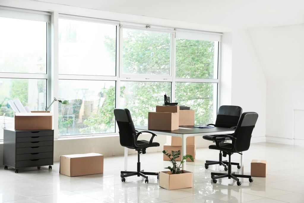 Cardboard boxes with belongings and furniture in new office on m